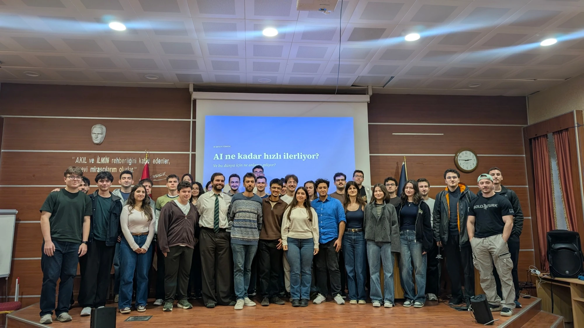 Yıldız Teknik Üniversitesi’ndeki söyleşinin ardından, “AI ne kadar hızlı ilerliyor?” yazılı sunum perdesinin önünde toplu fotoğraf veren katılımcılar